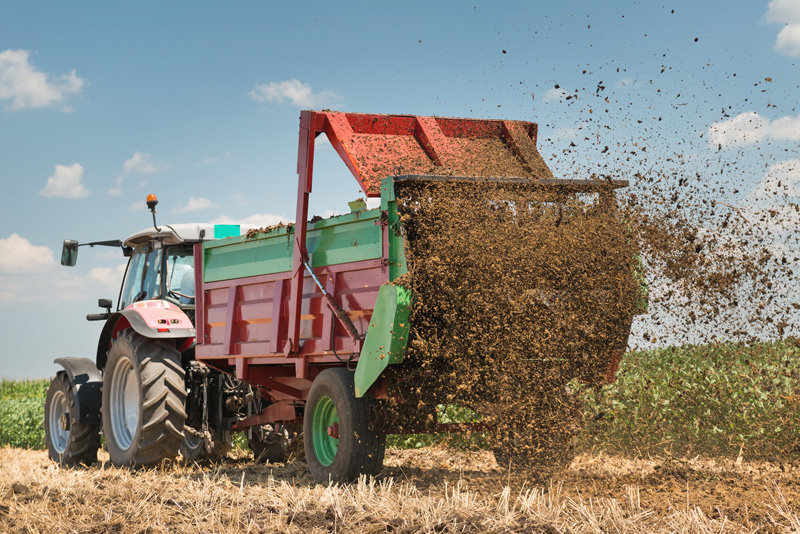 Traktor som gödslar ett fält