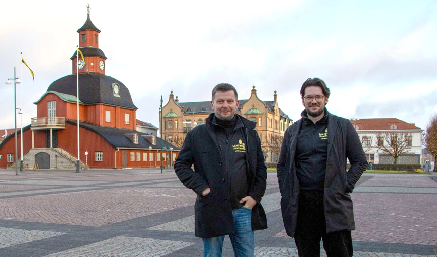 Två män står på torget i Lidköping framför Rådhuset.