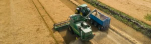 Skördetröska och traktor med släpp skördar åker.